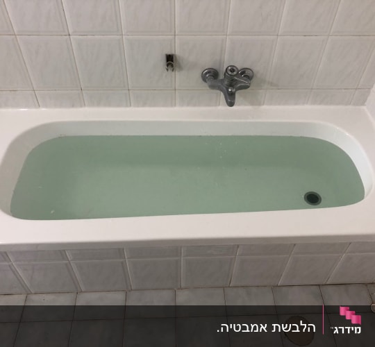 אמבטיה מלאה מים עם חיפוי אריחים לבנים